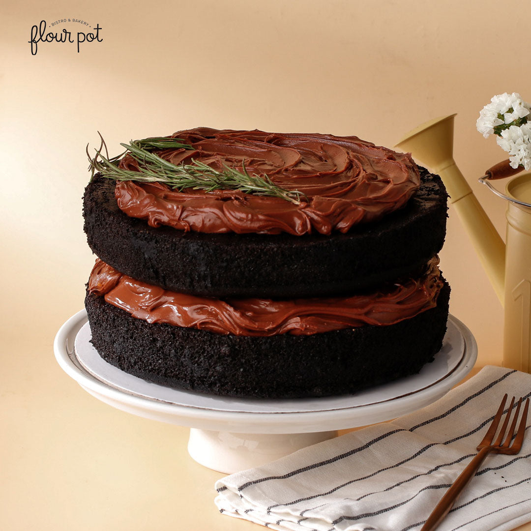 Earl Grey chocolate layer cake with glossy chocolate frosting and rosemary garnish