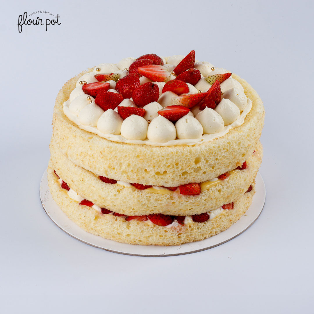Triple-layer strawberry shortcake with fluffy vanilla sponge, fresh strawberries, and whipped cream dollops, crowned with gold pearls