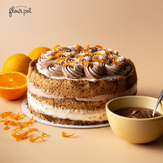Mocha cake layered with whipped cream and chocolate buttercream, topped with candied orange peel