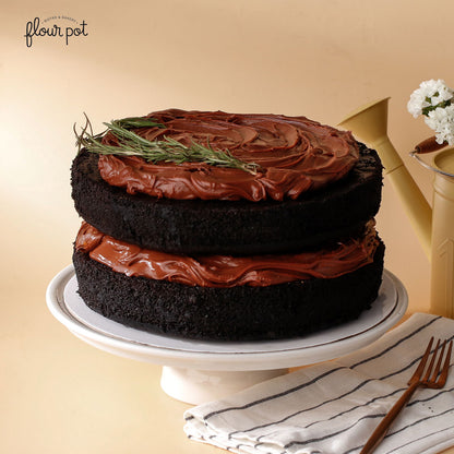 Earl Grey chocolate layer cake with glossy chocolate frosting and rosemary garnish